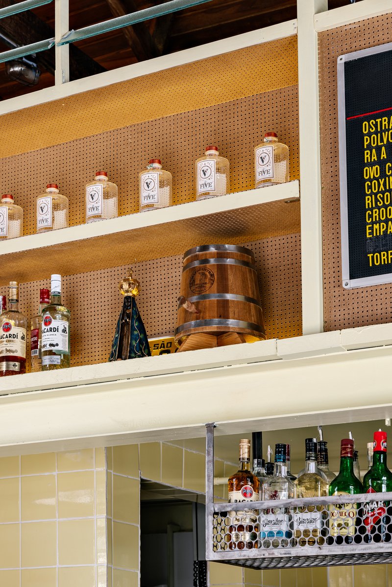 Detail of pegboard shelving with glass jars and wooden barrel beneath digital menu screen