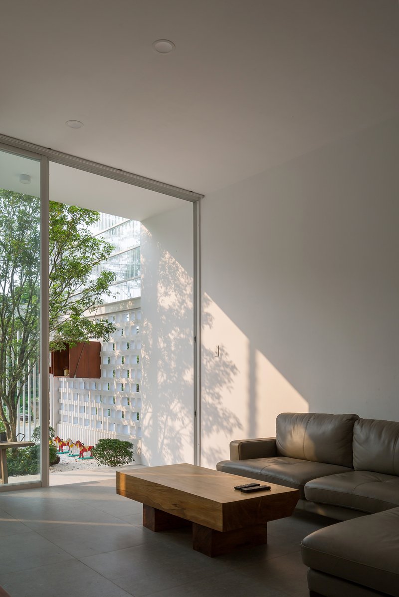 Living room with floor-to-ceiling glazing overlooking a courtyard with bamboo and perforated white screen wall