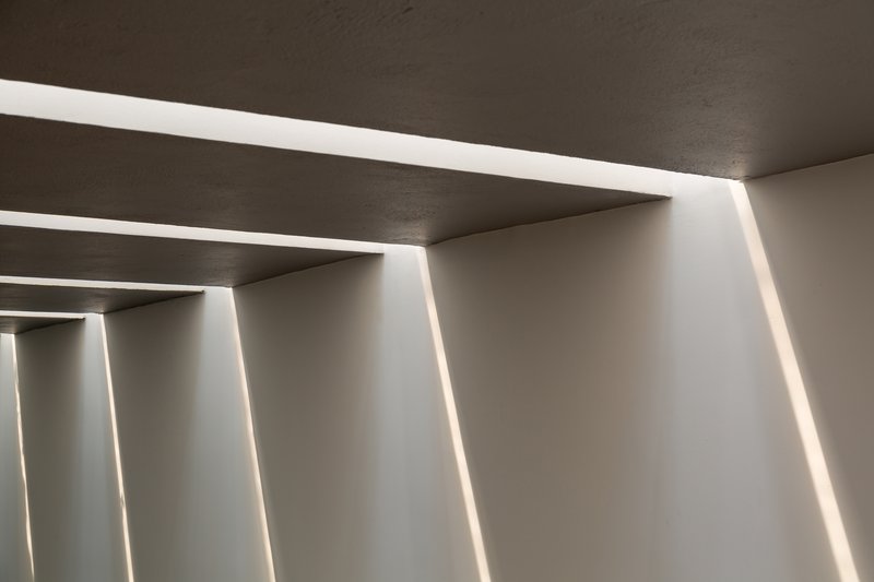 Close-up of recessed linear ceiling lights creating parallel bands of illumination across concrete soffit