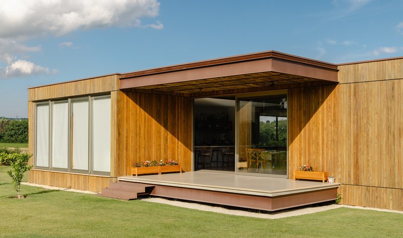 Covered terrace with exposed wood rafters beneath a copper-wrapped canopy and timber sliding door entry