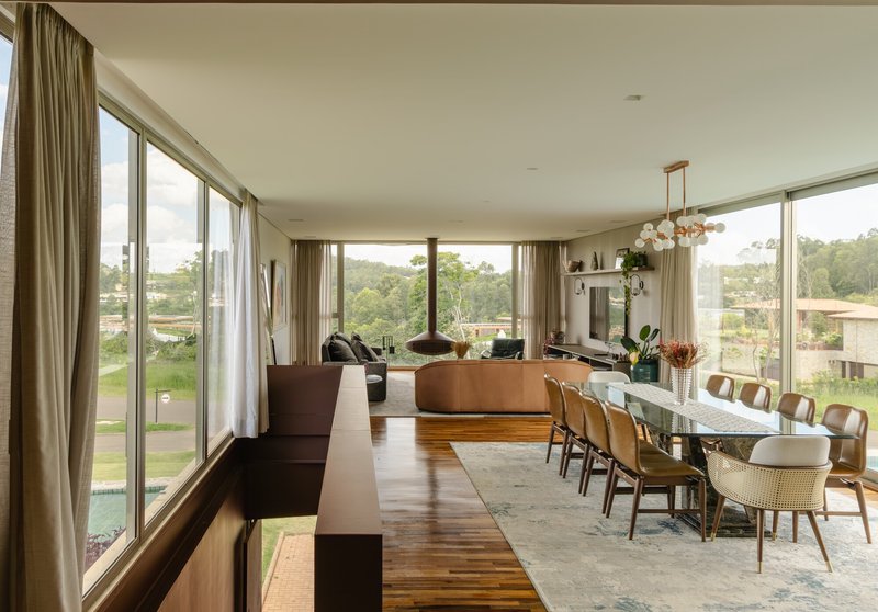 Open-plan dining and living space with full-height glazing on three sides overlooking surrounding hills