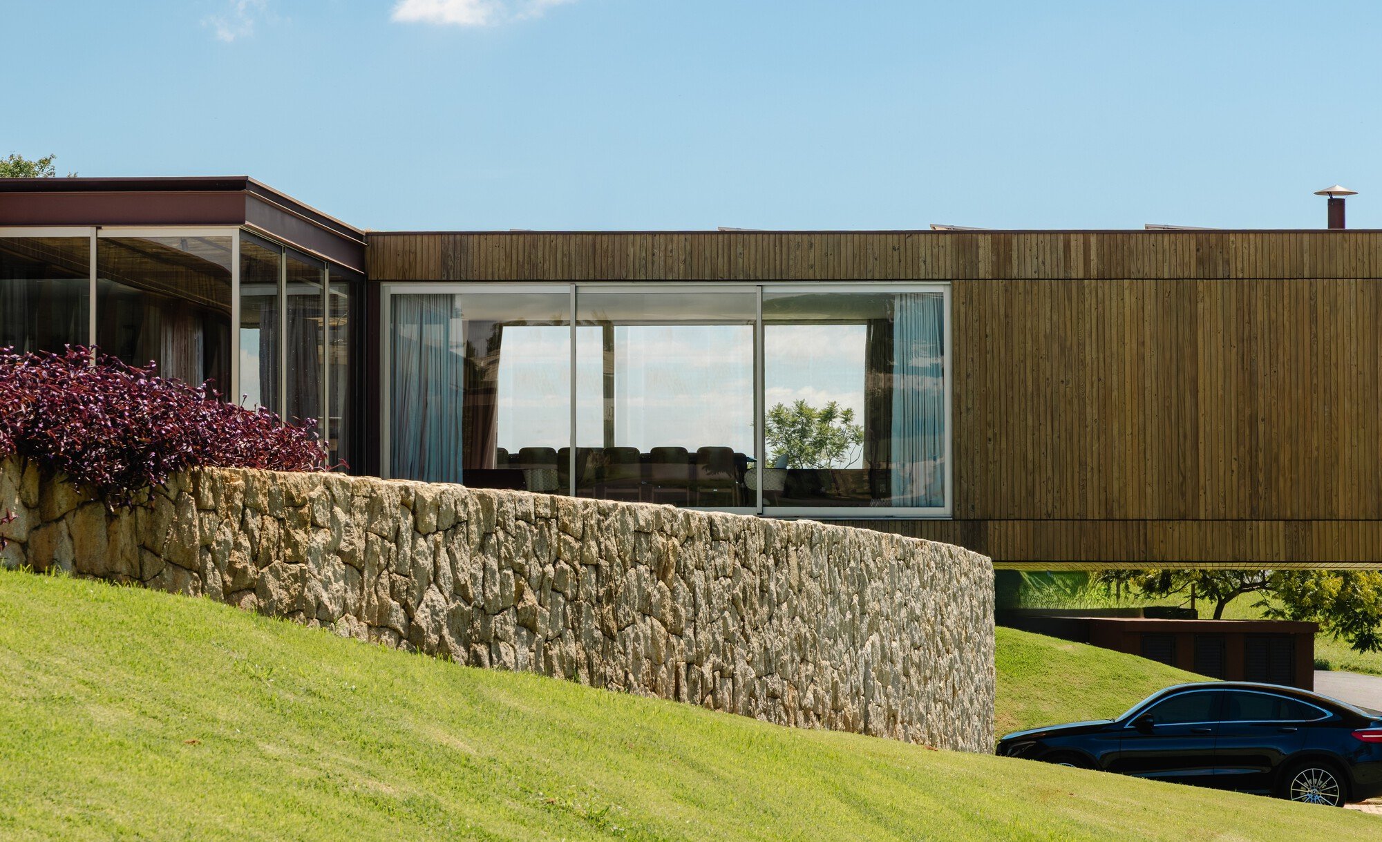 Sergio Sampaio and Tectônica Float a Timber Country House Over a Stone Plinth in Rural Brazil