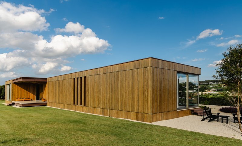 Side elevation showing vertical timber slat screen detail and corner glazing under cumulus clouds