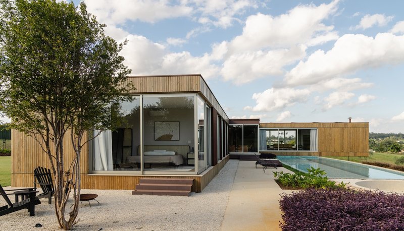 Courtyard view linking bedroom volume with pool wing through paved terrace and planted purple groundcover beds