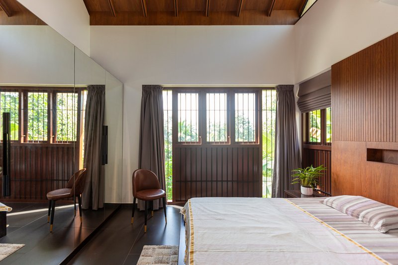 Bedroom with wood-paneled gabled ceiling and gridded windows framing the garden beyond
