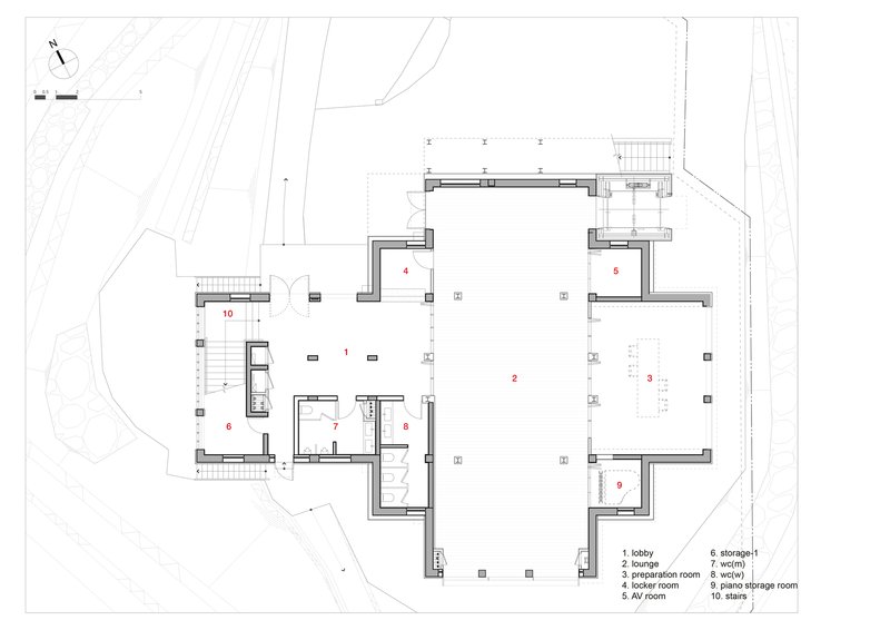 Floor plan drawing depicting a large central lounge space with surrounding service rooms and curved site boundary