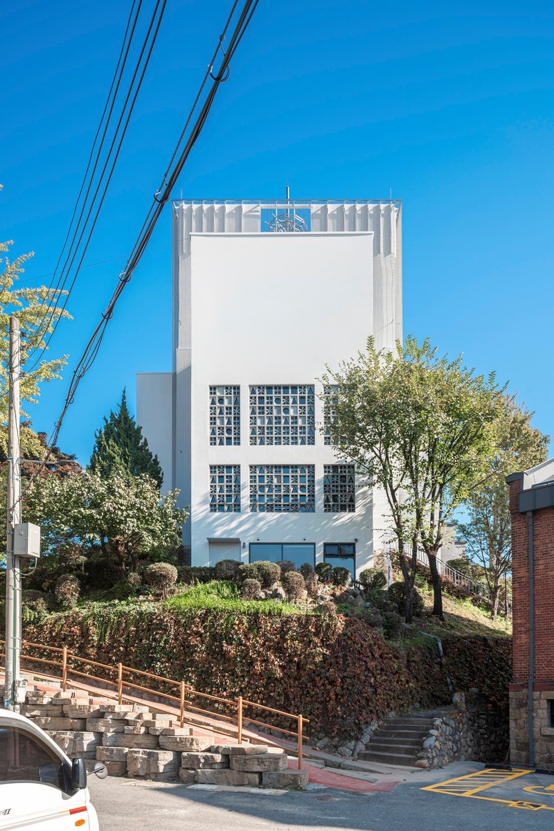 Front elevation showing glass block windows and ribbed metal canopy at the base with overhead power lines