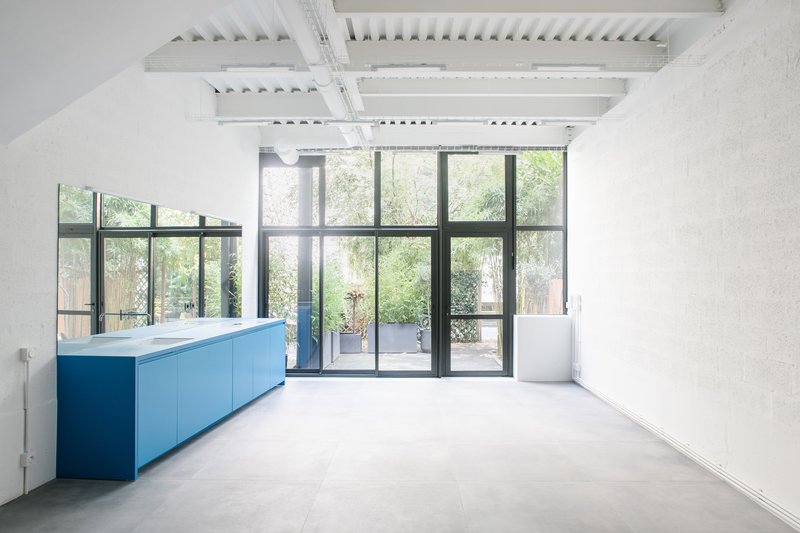 Living area with exposed white ceiling joists and steel-framed glazed doors opening to a planted courtyard