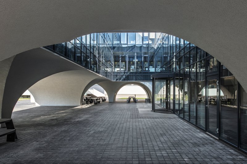 View through curved arch to glazed facade and covered passageway with layered arched openings