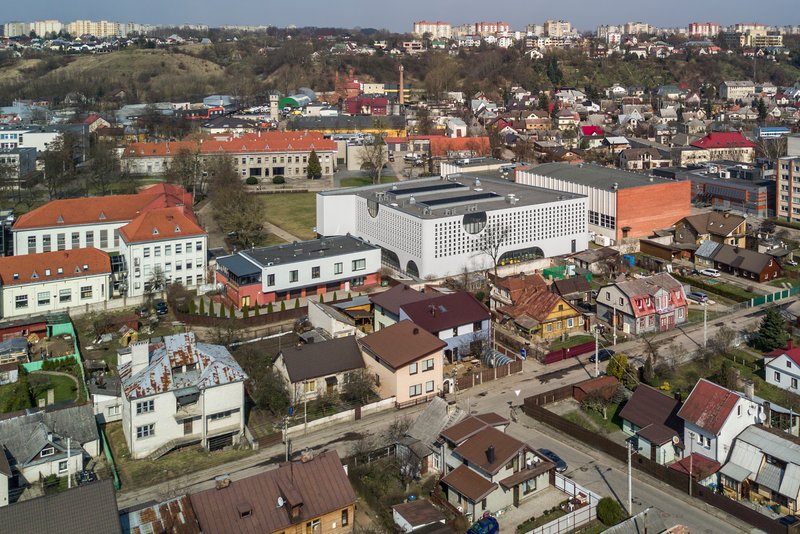 Aerial view of the white perforated volume rising above surrounding residential rooftops in early spring