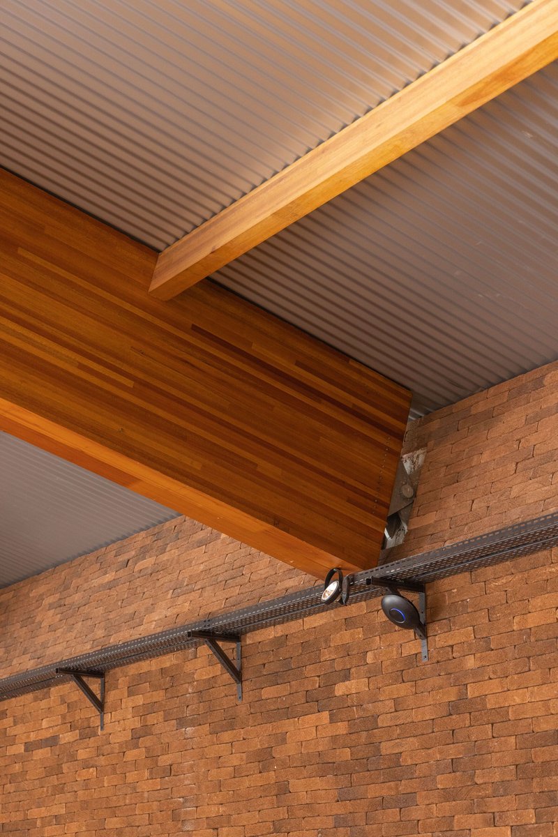 Detail of the timber beam junction with corrugated metal ceiling and exposed brick wall below