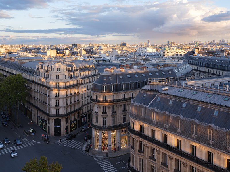 Aerial view of mansard rooftops and the curved corner building at street intersection during golden hour