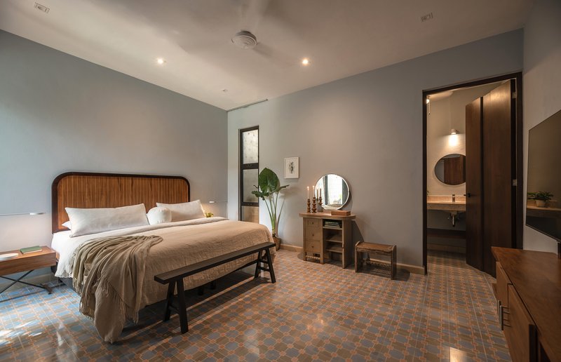 Bedroom with patterned terracotta floor tile and view through doorway to ensuite bathroom