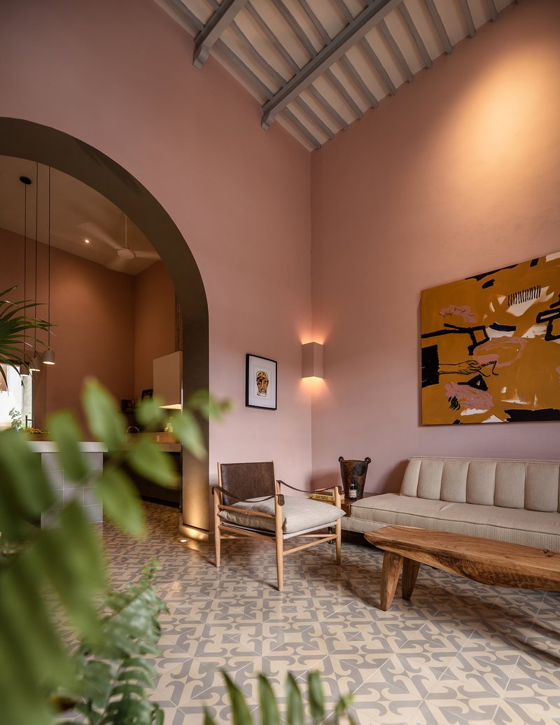 Living room with arched doorway, vaulted timber ceiling, patterned tile floor and foliage in foreground