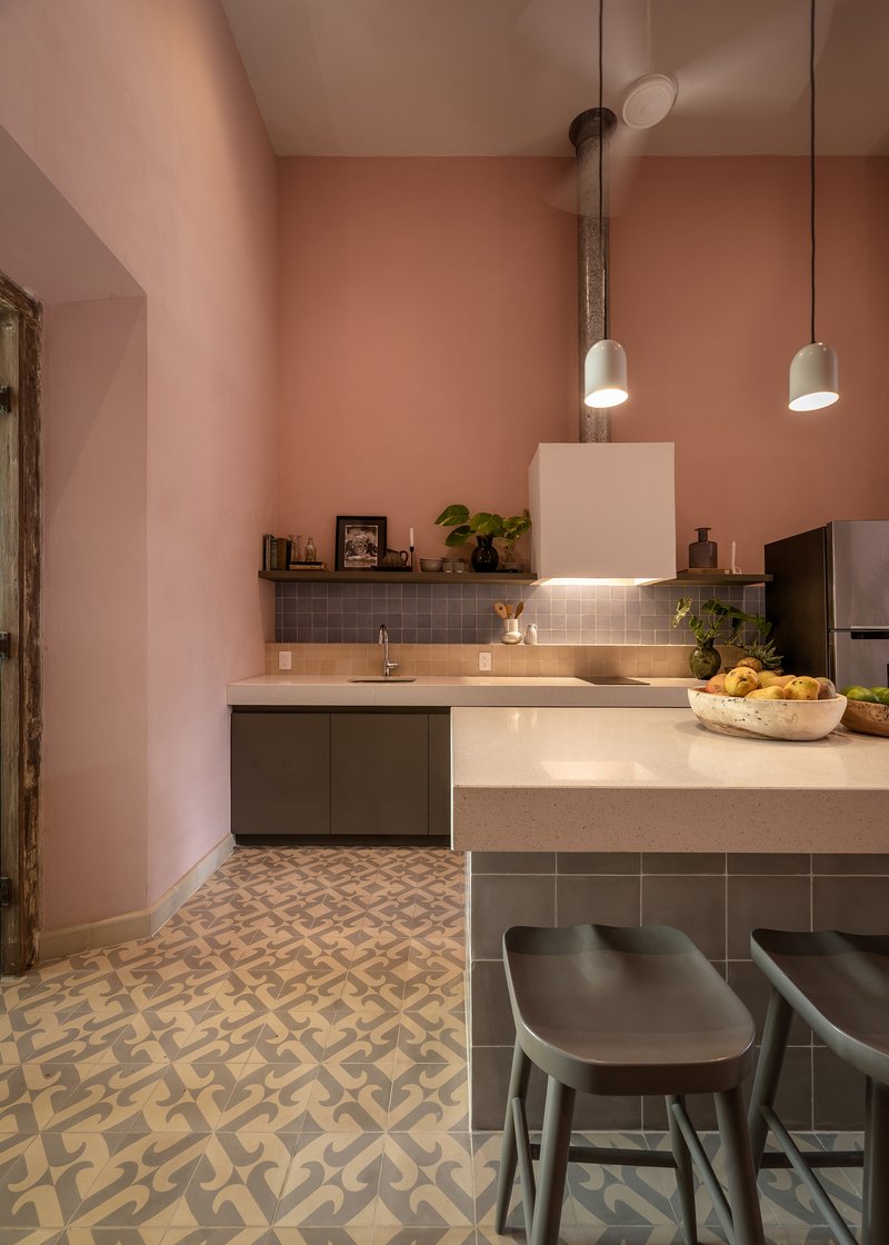 Kitchen island with grey tile base and pendant lights suspended from an exposed industrial pipe