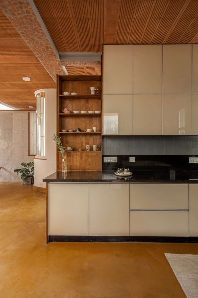 Kitchen with beige lacquered cabinets, black countertop and timber ceiling with exposed brick detail