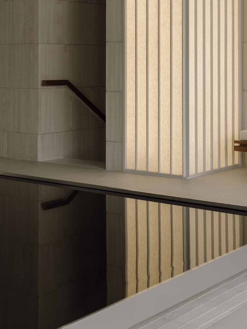 Interior stairwell with vertical timber cladding and black metal handrails spanning multiple levels