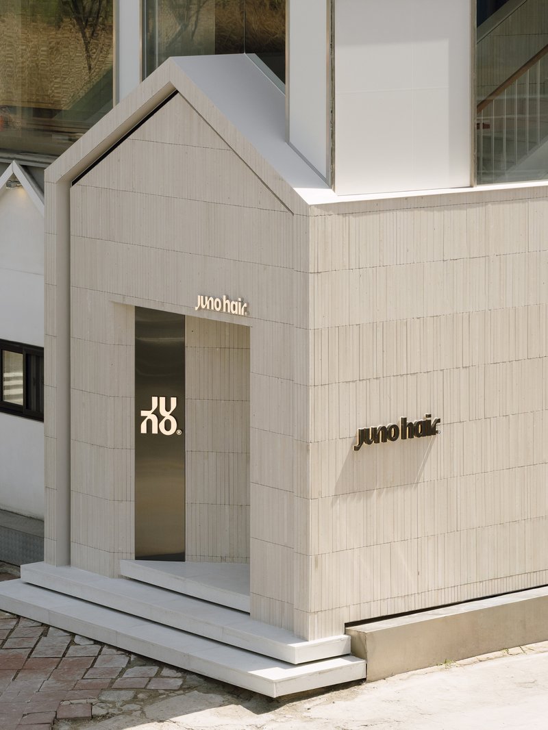 Street corner facade with gabled volume clad in vertical timber strips and recessed glass entrance