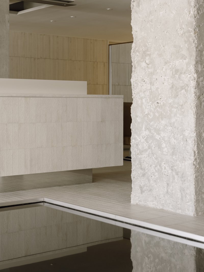 Close-up of textured white concrete column beside a pale tiled reception desk