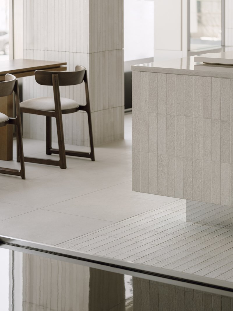 Detail of the junction between pale tiled salon counter and reflective dark glass surface