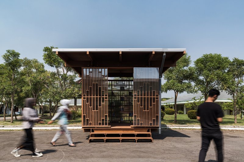Front elevation of the timber pavilion showing sliding screen panels and pedestrians crossing the paved area