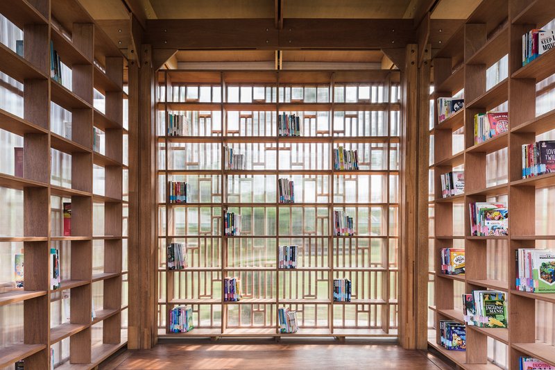 Floor-to-ceiling timber screen wall with integrated bookshelves framing the interior library space