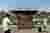 This architectural image showcases a modern pavilion with a distinctive wooden screen facade. The ge