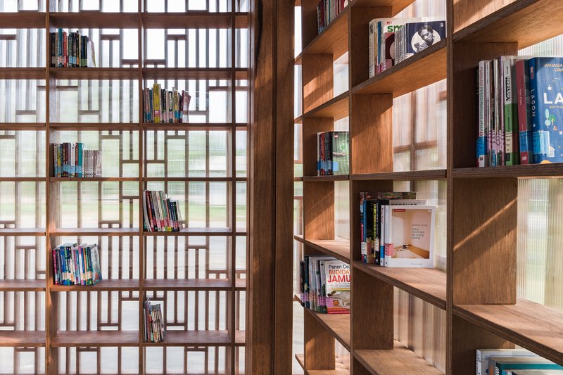Interior bookshelves alongside patterned timber screen with diffused daylight filtering through translucent panels
