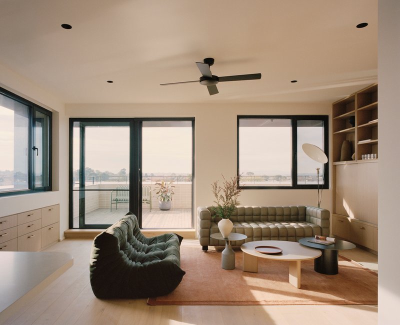 Living room with dark-framed sliding doors opening to a terrace and built-in timber shelving at right