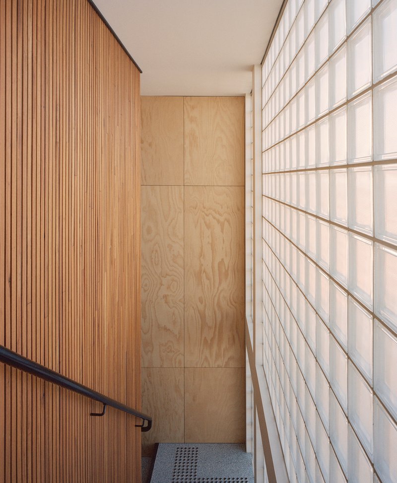 Narrow stairwell with timber slat wall and translucent glass block partition