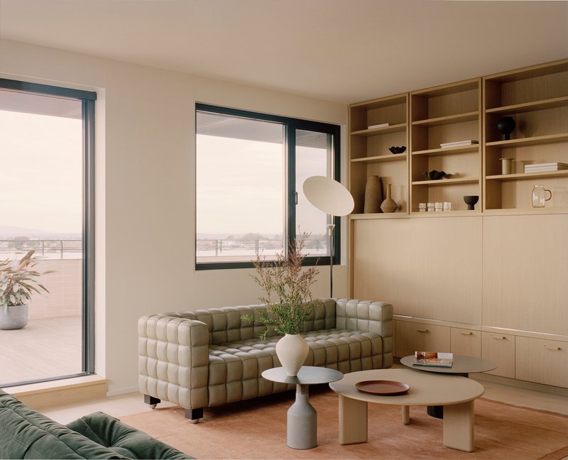 Living room with plywood shelving unit, quilted sofas and terrace access
