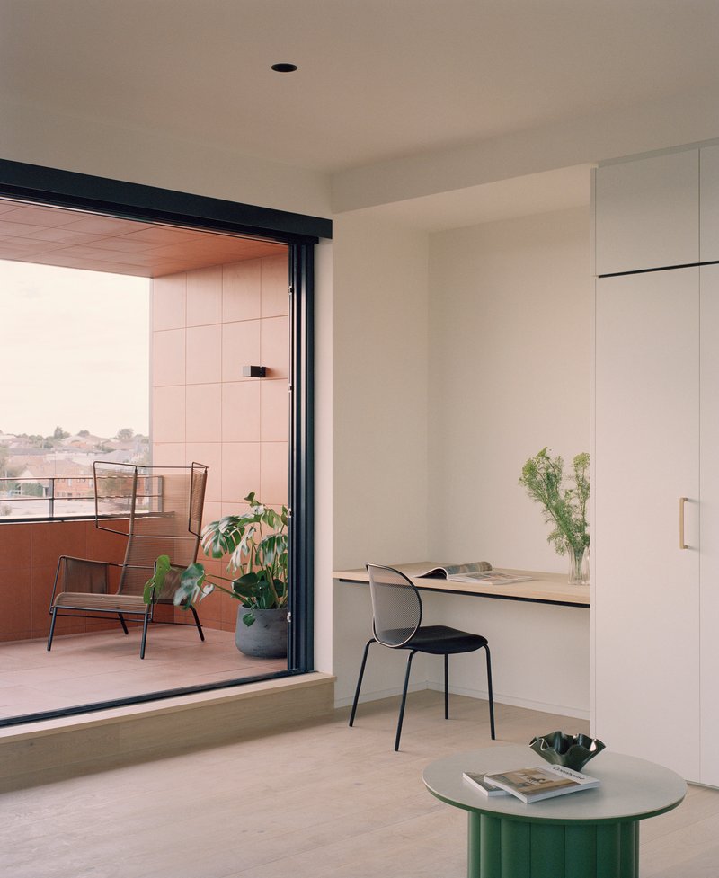 Built-in desk and storage unit beside a glazed door opening to a terrace with potted plants