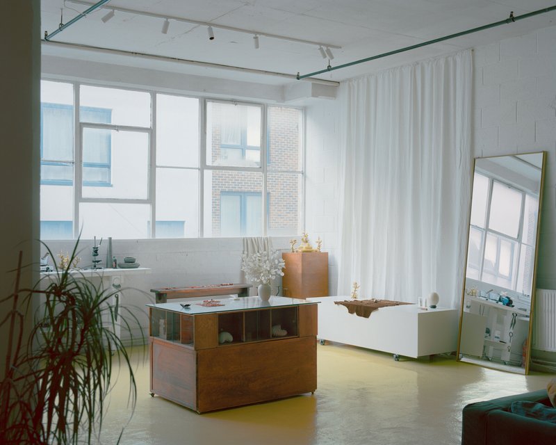 Open studio space with yellow resin flooring and large gridded windows framing brick buildings