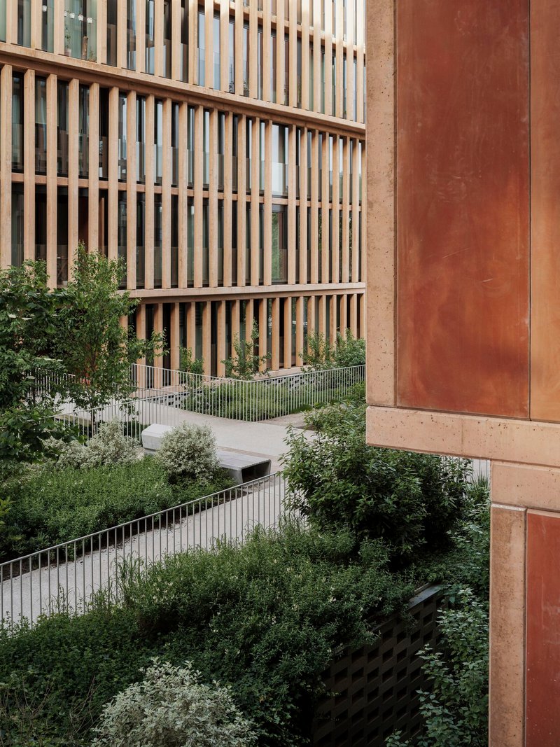 Terraced planted balconies with metal railings between timber screened facades and weathered steel panels