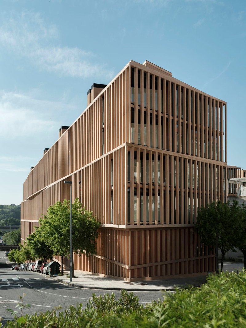 Corner view of the vertical timber screen facade under a blue sky with scattered clouds