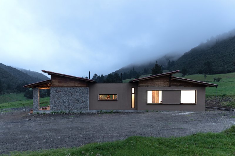 Side elevation showing illuminated window openings and timber roof overhangs in evening fog