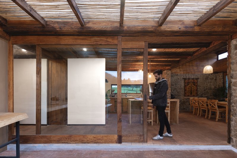 Interior view through timber-framed glass partitions with a person standing near the dining space