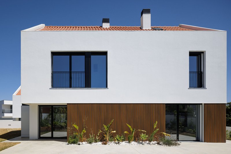 Garden elevation with timber slat cladding at ground level and planted bed with palms beneath clay tile roof