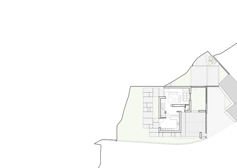 Site plan drawing showing single building footprint with pitched roof outline on sloped terrain
