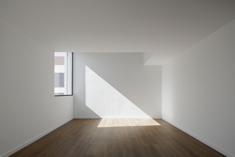 White room with timber floor and diagonal shaft of sunlight through corner window