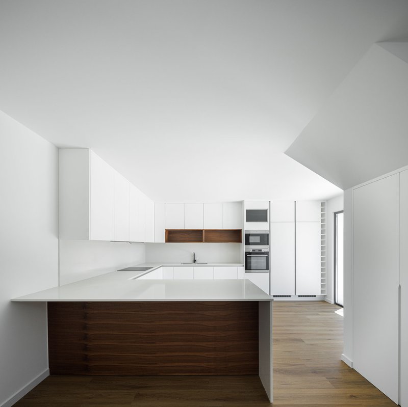Kitchen with white cabinetry, walnut timber island, and light oak flooring under sloped ceiling