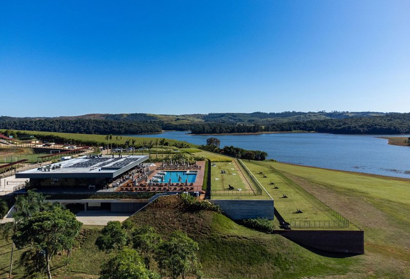 Aerial view of grass-roofed accommodation wings stepping down the hillside toward the lake