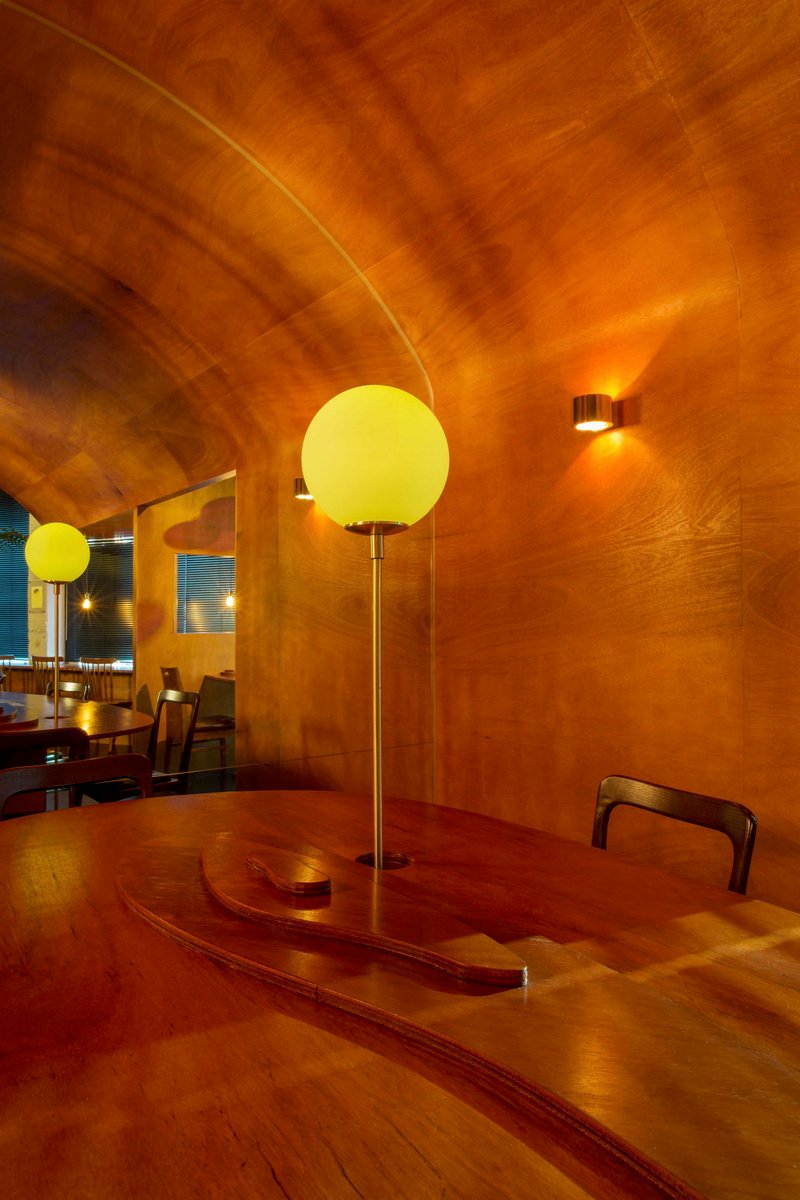 Detail of the laminated wood barrel vault curving above a spherical pendant and curved table edge