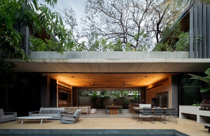 Open pavilion with timber soffit framing a view through to the dining area beyond the pool