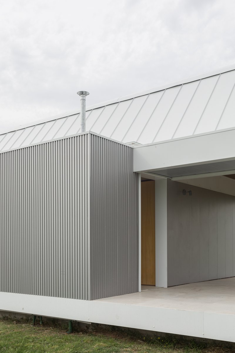 Detail of the corrugated metal wall meeting the sloped metal roof with a steel flue pipe
