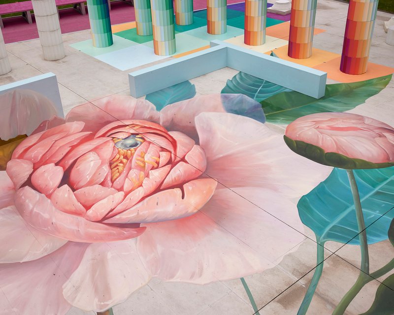 Ground-level view of the floor mural depicting a pink peony blossom with rainbow columns in the background