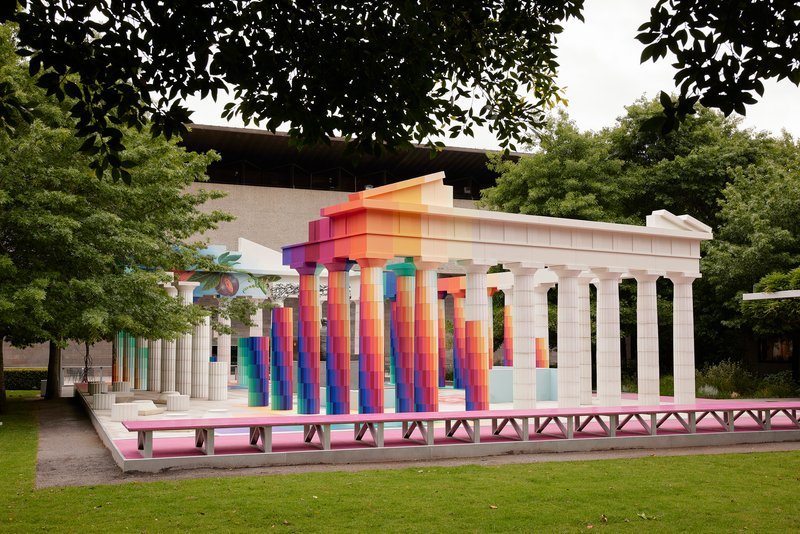 Side view of the pavilion with white fluted columns and gradient-painted entablature in a lawn setting