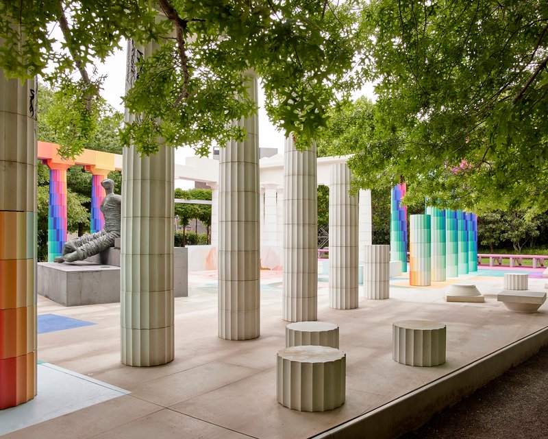 Interior view of the colonnade showing fluted cylindrical seats and gradient columns under leafy branches