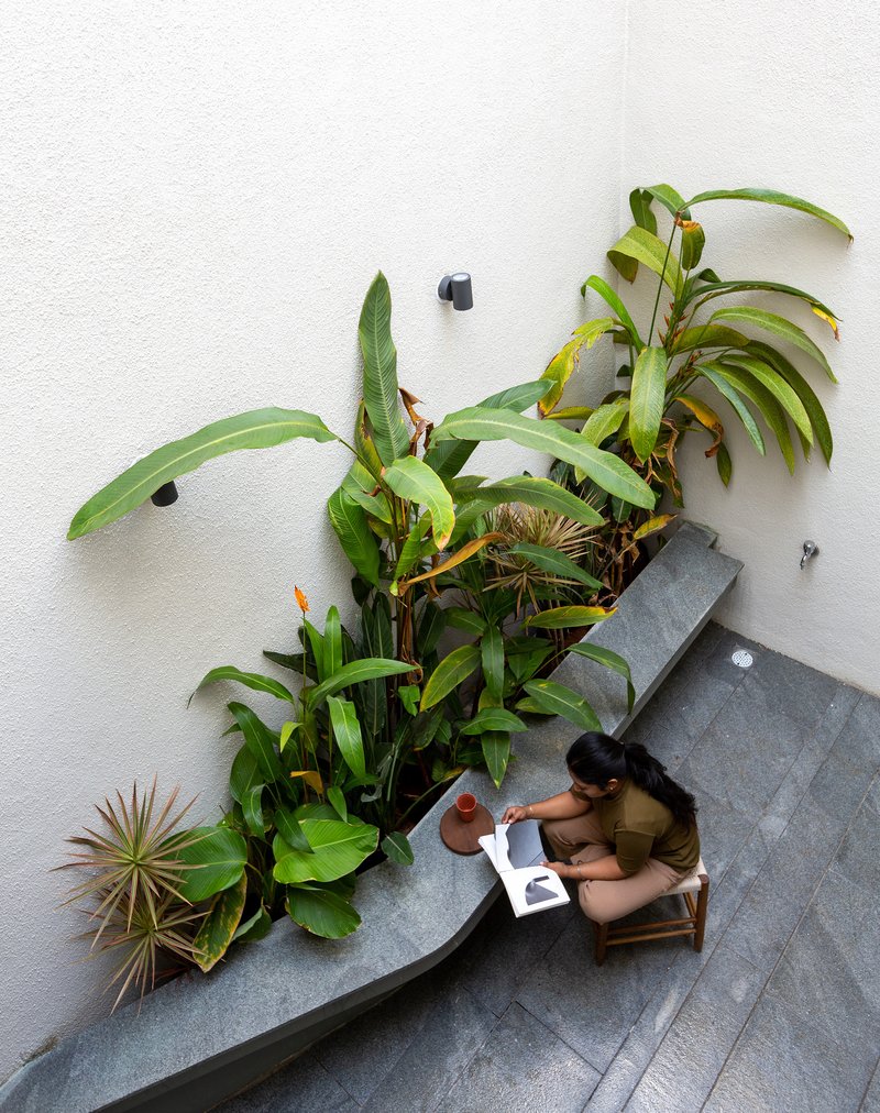 Overhead view of person seated at stone bench beside planted bed in interior courtyard