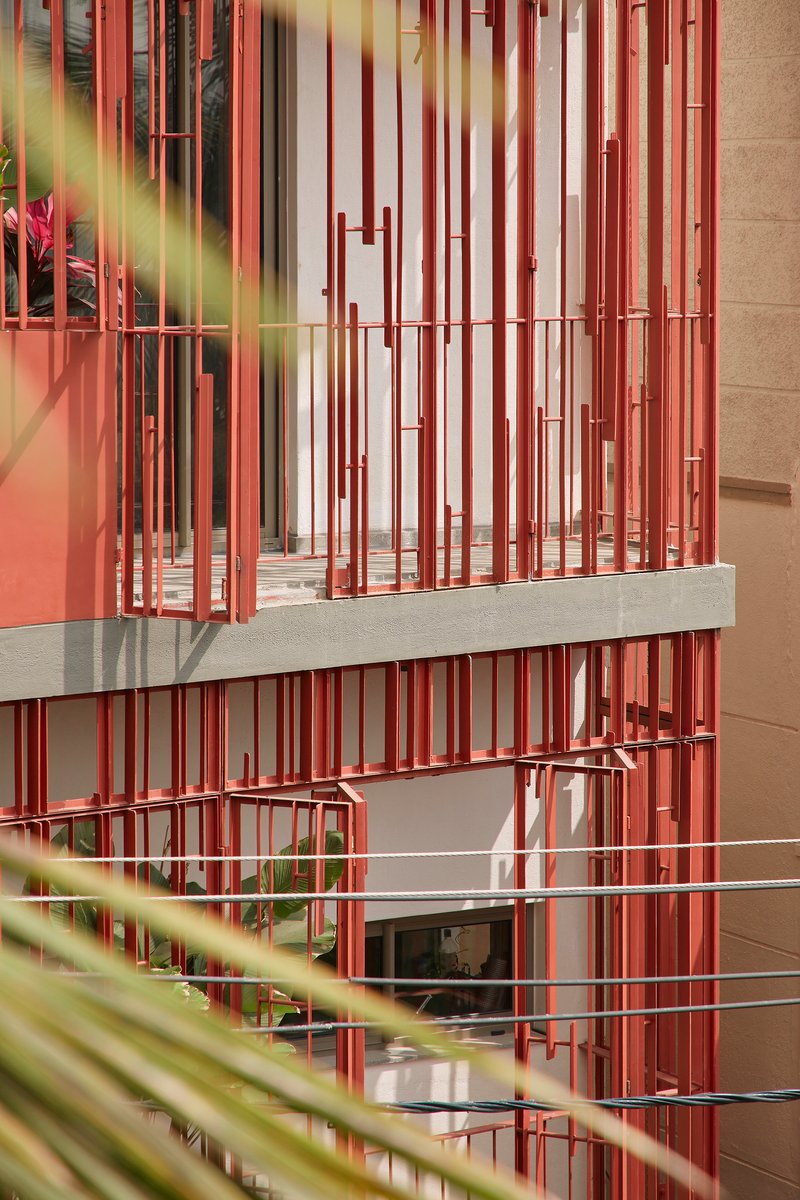 Layered view of red batten screens across multiple levels framed by green foliage